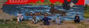 Velvet Scoter duck mural with team who are protecting it sitting in front of it.