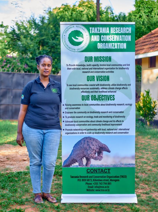 Conservationist standing by charitable poster from Tanzania Research and Conservation Organization